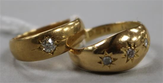 A late Victorian 18ct gold and gypsy set solitaire diamond ring and a similar George V three stone diamond ring.